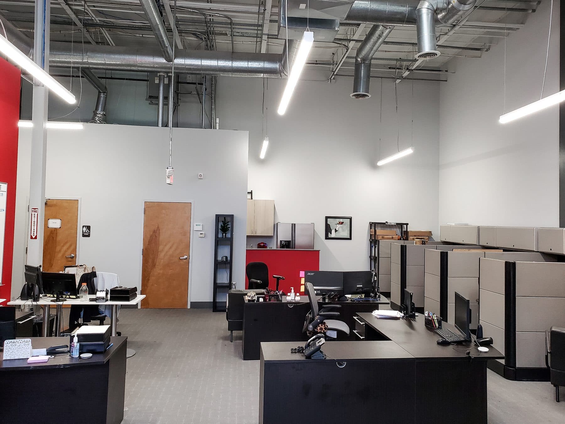 Open office with suspended linear LED fixtures over desks